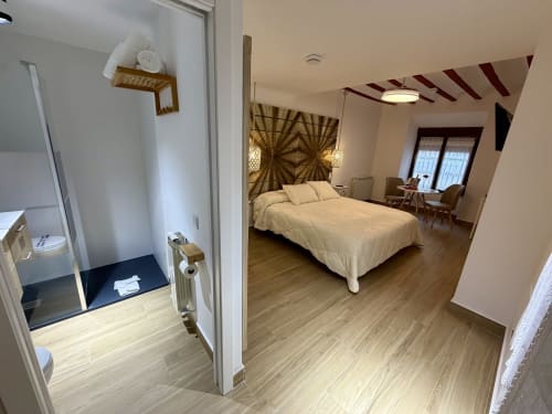 Modern bedroom at Complejo Turístico Retiro del Teatro with queen bed, wooden flooring, en-suite bathroom, and city views in