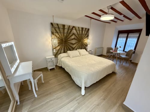 Modern bedroom in Almagro hotel with queen bed, white furniture, wooden floors, decorative gold headboard tapestry, and city
