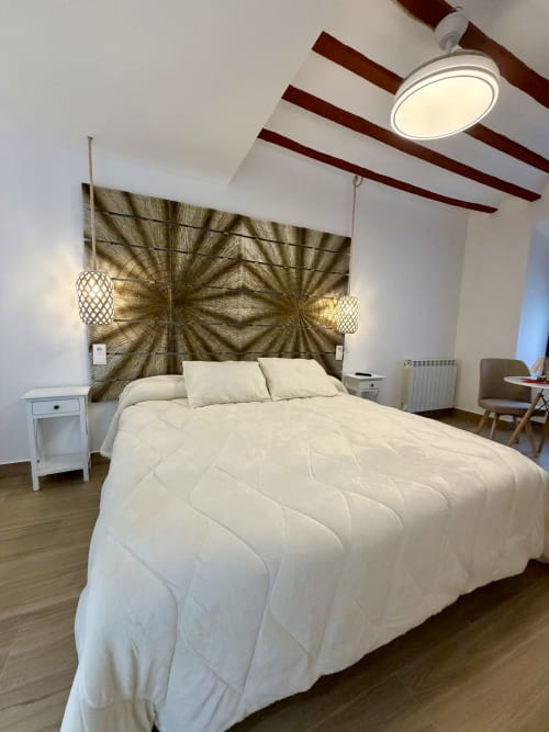 Modern bedroom at Retiro del Teatro in Almagro with cream bedding, patterned headboard, and wooden ceiling beams
