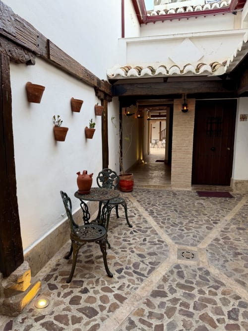 Charming courtyard at Complejo Turístico Retiro del Teatro in Almagro with stone patio, wrought iron seating, and terracotta
