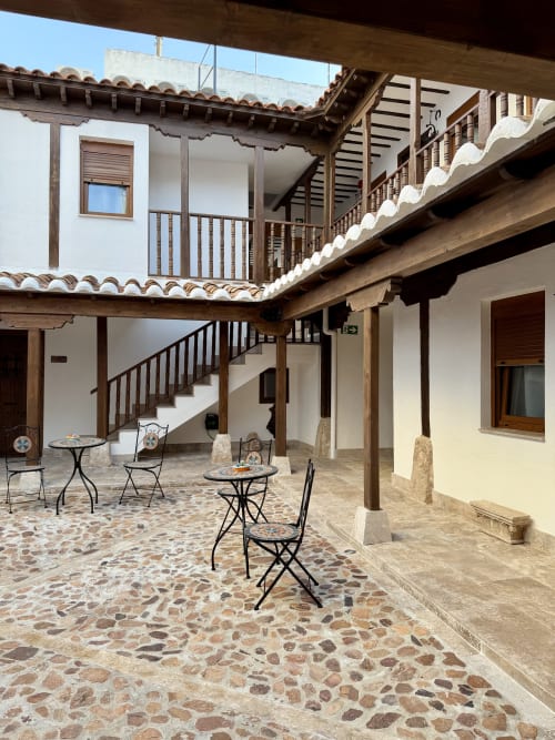 Colonial courtyard at Complejo Turístico Retiro del Teatro in Almagro with white buildings, wooden railings, terracotta roof