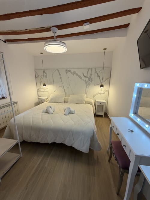 Modern bedroom at Complejo Turístico Retiro del Teatro in Almagro with queen bed, marble headboard, wooden beams, and city