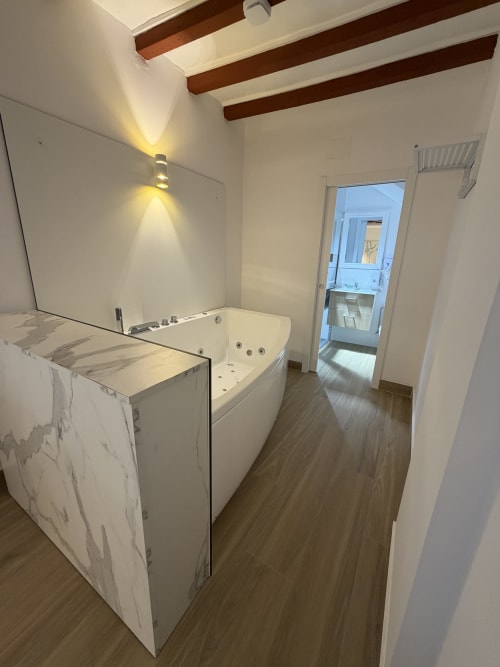 Modern bathroom with white soaking tub, marble vanity, and exposed wooden beams at Complejo Turístico Retiro del Teatro,