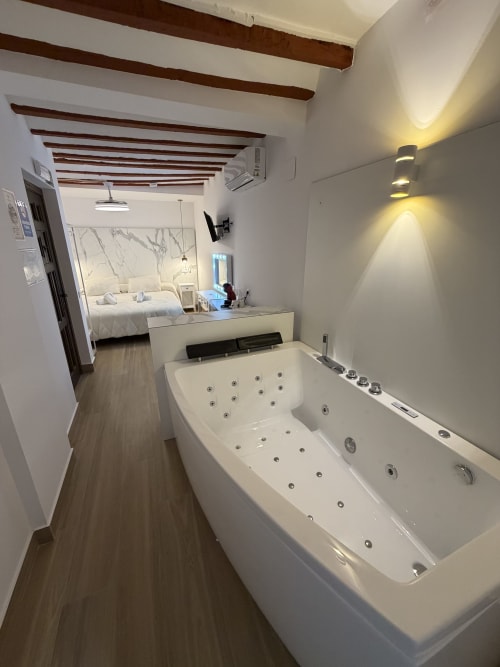 Luxury spa bathroom with jetted tub overlooking bedroom at Complejo Turístico Retiro del Teatro hotel in Almagro, Ciudad Real