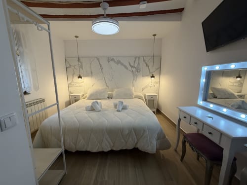 Modern bedroom at Complejo Turístico Retiro del Teatro in Almagro with queen bed, marble headboard, and vanity mirror with