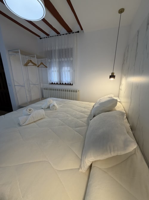 Modern bedroom at Complejo Turístico Retiro del Teatro in Almagro with white linens, wooden beams, skylight, and contemporary
