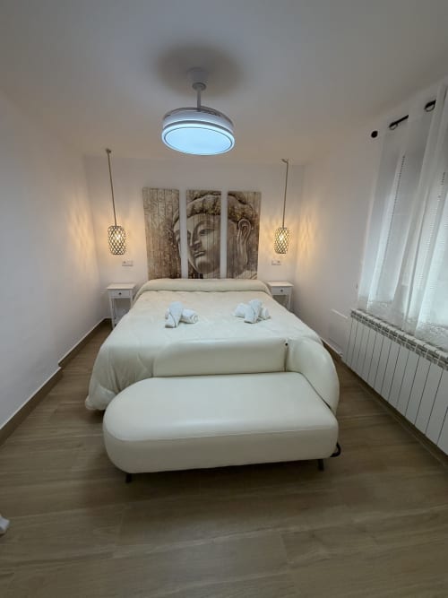 Modern bedroom at Complejo Turístico Retiro del Teatro in Almagro with white bed, pendant lights, and wooden flooring