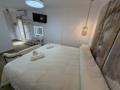 Modern bedroom at Complejo Turístico Retiro del Teatro in Almagro with white bed, TV, pendant light, and decorative wooden