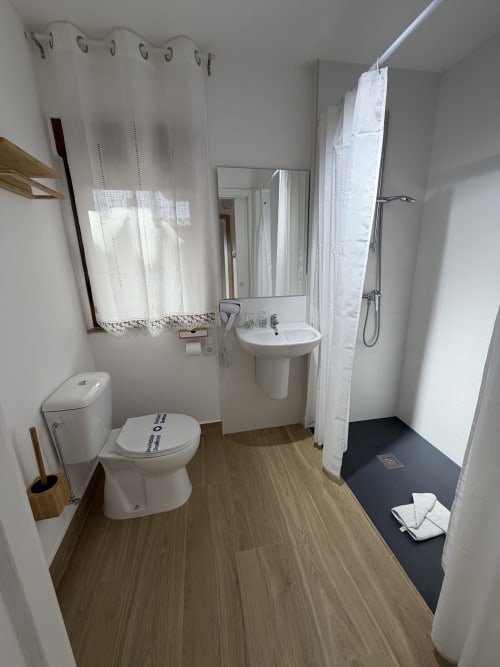 Modern bathroom at Complejo Turístico Retiro del Teatro, Ciudad Real. White fixtures, wood-grain flooring, shower area.