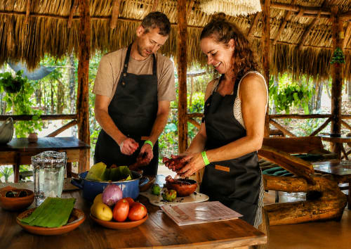 Dos chefs preparan ingredientes frescos en la cocina rústica del Hotel Boutique Cenote Secreto Maya, Valladolid Yucatán.