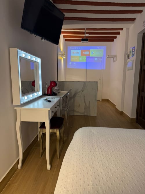 Modern hotel room at Complejo Turístico Retiro del Teatro with bed, vanity mirror, TV displaying streaming apps, and wooden