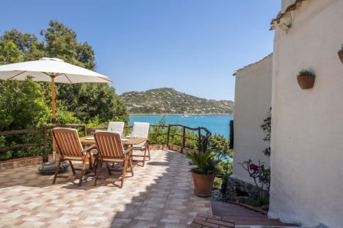 Terrazza di villa fronte mare in Sardegna con lettini, ombrellone e vista sul mare turchese