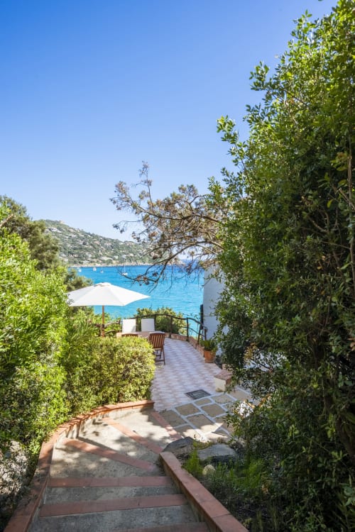 Sentiero della villa costiera con giardino mediterraneo che conduce alla terrazza con vista sul mare turchese, Top Villas Sardegna