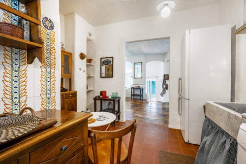 Luminosa cucina della villa sarda con mobili in legno, elettrodomestici bianchi e pavimenti in cotto