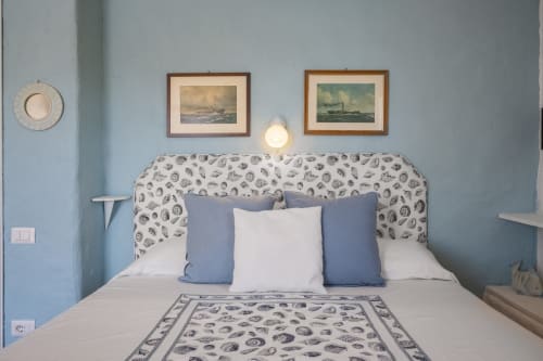 Camera da letto con tema costiero a Top Villas Sardinia: testata con motivi conchiglie, pareti blu e quadri nautici