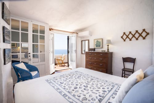 Camera da letto luminosa con vista sul mare a Top Villas Sardegna, con biancheria bianca, arredi in legno e accesso al balcone.