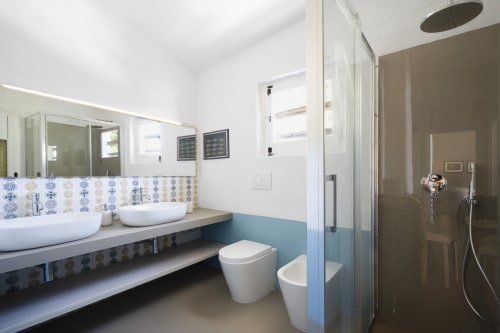 Bagno moderno di Top Villas Sardegna con doppi lavandini, doccia walk-in e dettagli in piastrelle blu