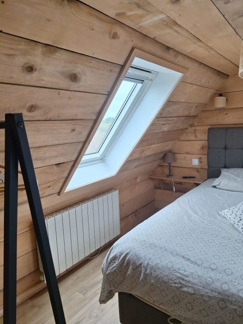 Attic bedroom with skylight in Gîte Kerroc'h cottage at Le Village Du Moulin, Sizun, featuring wooden beams and radiator