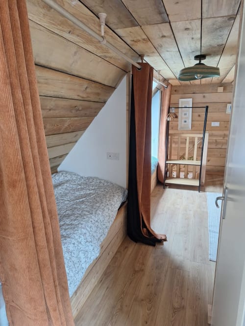 Cozy wooden cottage bedroom interior at Le Village Du Moulin, Sizun, with bed, wooden beams, and modern amenities