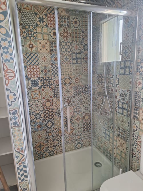 Modern shower enclosure with decorative Moroccan tile pattern walls in blue, terracotta and cream at Le Village Du Moulin