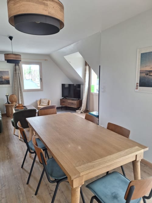 Modern cottage dining area at Le Village Du Moulin, Sizun, with wooden table, contemporary chairs, and living space