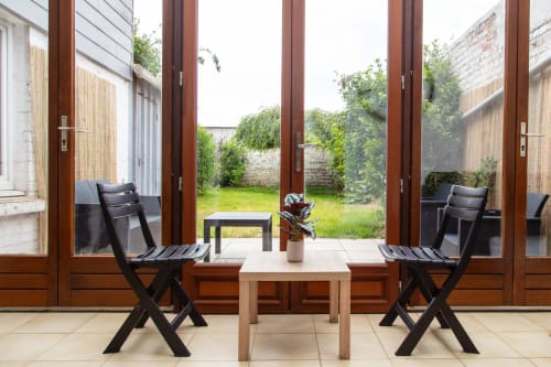 Appartement avec vue sur jardin, terrasse, portes en bois, chaises noires et jardin luxuriant au BALI ROOM, La Valette du Var