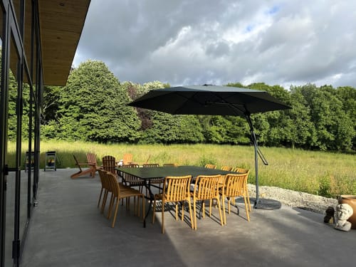 Garden patio with dining table, yellow chairs, and black umbrella at Le Village Du Moulin B&B in Sizun