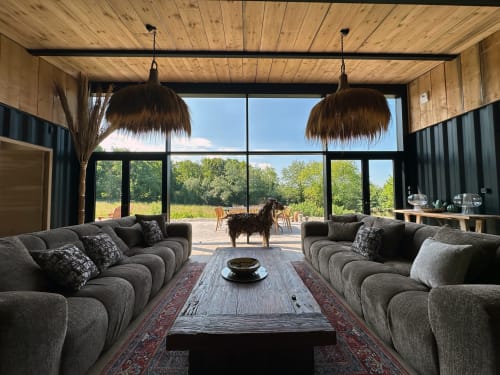Modern cottage lounge at Le Village Du Moulin, Sizun with curved sofas, wooden ceiling, pendant lights, and garden views