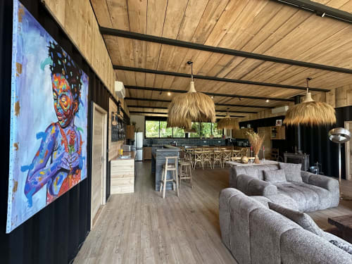 Modern cottage living area at Le Village Du Moulin in Sizun with gray sofa, kitchen, and colorful artwork on TV