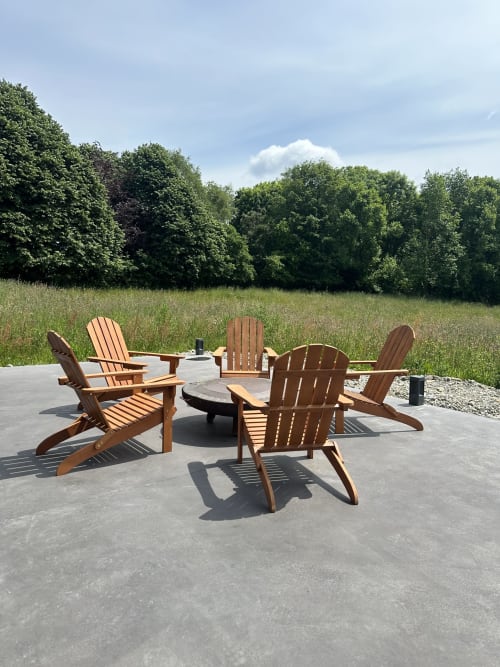 Wooden Adirondack chairs around fire pit on patio overlooking meadow at Le Village Du Moulin cottage