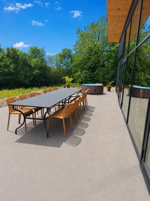 Modern patio at Le Village Du Moulin cottage with dining table, wooden chairs, hot tub, and forest views in Sizun