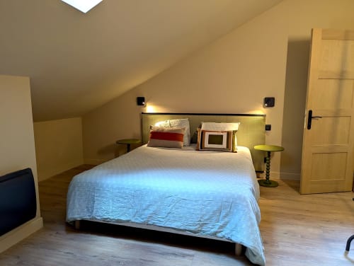 Chambre moderne à la Domaine Alga B&B à Bourg-Charente avec lit, lampes de lecture, tables de nuit et porte en bois