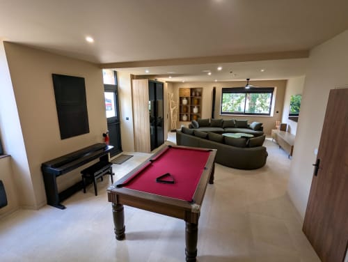 Salle de jeux moderne au Domaine Alga avec billard, piano, canapé noir et grandes fenêtres à Bourg-Charente