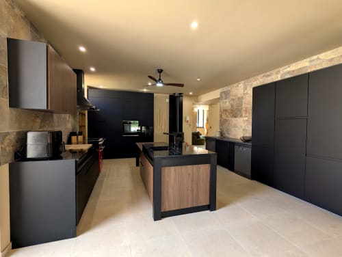 Cuisine moderne du Domaine Alga B&B à Bourg-Charente avec armoires noires, îlot en bois et accents en pierre