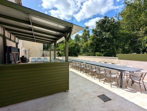 Domaine Alga outdoor terrace with green bar counter, dining tables, and trees in Bourg-Charente