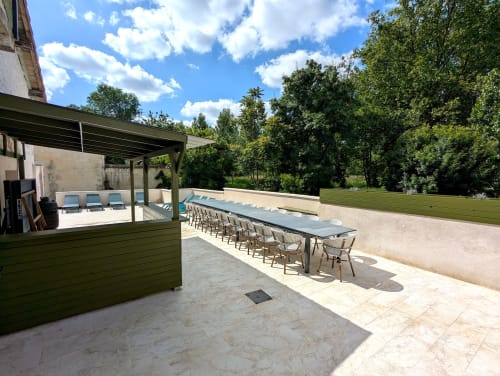 Terrasse extérieure du Domaine Alga avec table à manger, coin lounge et arbres verts à Bourg-Charente