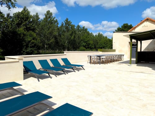 Terrasse du Domaine Alga avec transats bleus, espace repas et vue sur la forêt à Bourg-Charente