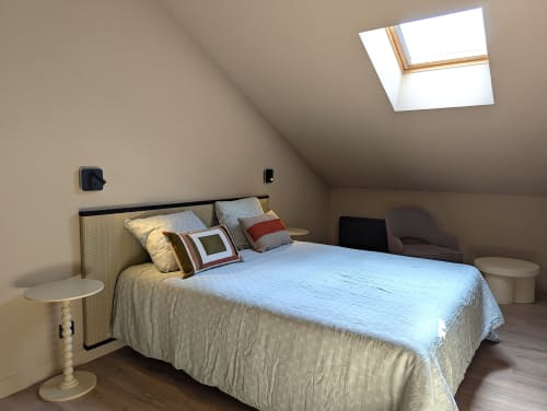 Chambre mansardée lumineuse au Domaine Alga avec puits de lumière, lit beige, coussins décoratifs, tables de nuit et parquet