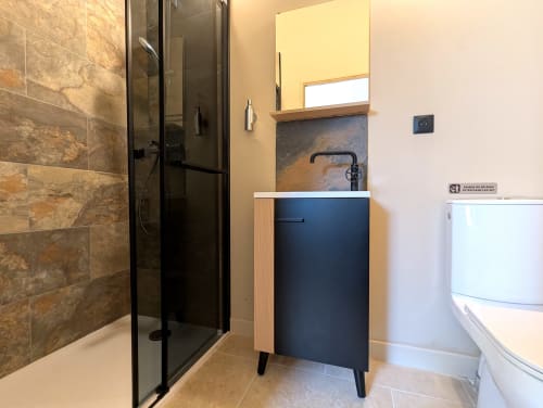 Salle de bains moderne du gîte Domaine Alga avec douche en ardoise, vasque bleu marine et toilettes blanches
