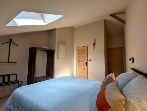 Chambre moderne de la Maison d'hôtes Domaine Alga à Bourg-Charente avec puits de lumière, portes en bois et décoration épurée