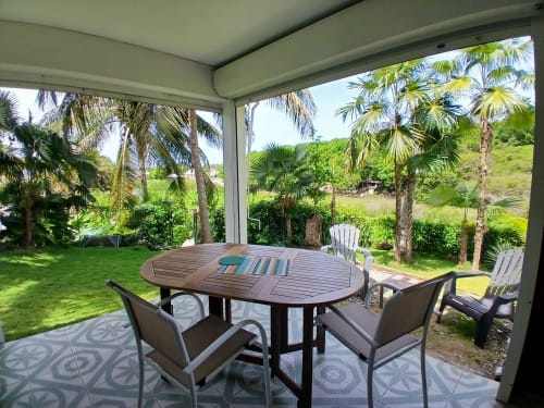 Patio couvert avec table à manger à Ti Village Créole, Sainte-Anne, vue sur jardin tropical et palmiers