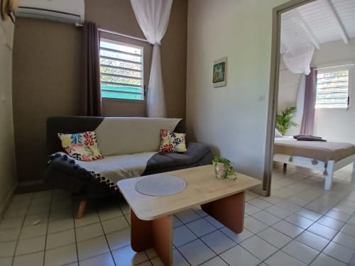 Ti Village Créole bungalow living room with sofa, coffee table, and garden view windows in Sainte-Anne, Guadeloupe