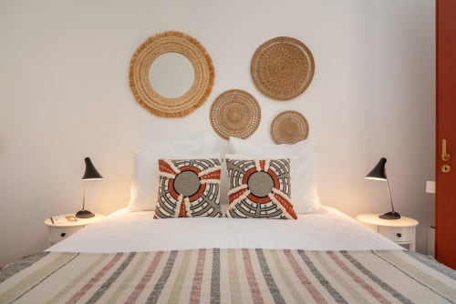 Quarto moderno em Monte das Açoteias com cestas tecidas na parede, almofadas estampadas e luminários de cabeceira