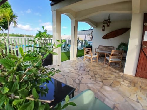 Ti Village Créole bungalow terrace with seating area, stone patio, garden view, and pool access in Sainte-Anne, Guadeloupe