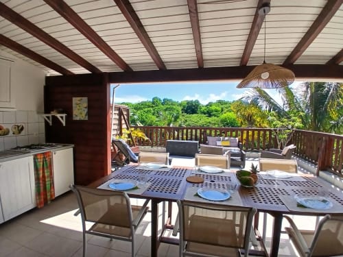 Ti Village Créole bungalow terrace with dining table, kitchen, garden views, and tropical vegetation in Sainte-Anne,