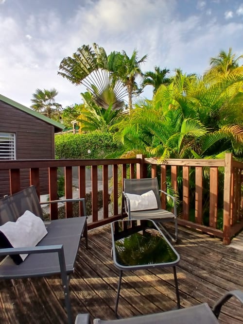 Wooden deck with lounge chairs overlooking tropical garden at Ti Village Créole bungalow, Sainte-Anne