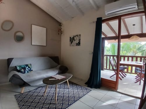Bungalow living room at Ti Village Créole, Sainte-Anne with sofa, patio doors, and garden view