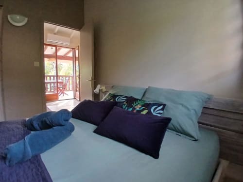Bedroom at Ti Village Créole bungalow in Sainte-Anne with bed, pillows, and open door to garden terrace