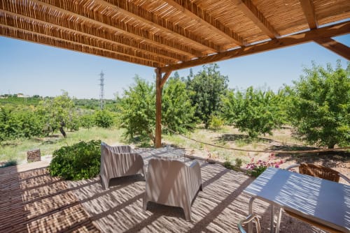 Pátio sombreado com pérgola e assentos com vista para os olivais em Monte das Açoteias em Tavira