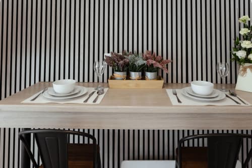 Modern dining setup at The Snug by JS Apartments in Blackburn with place settings, potted plants, and striped wall backdrop